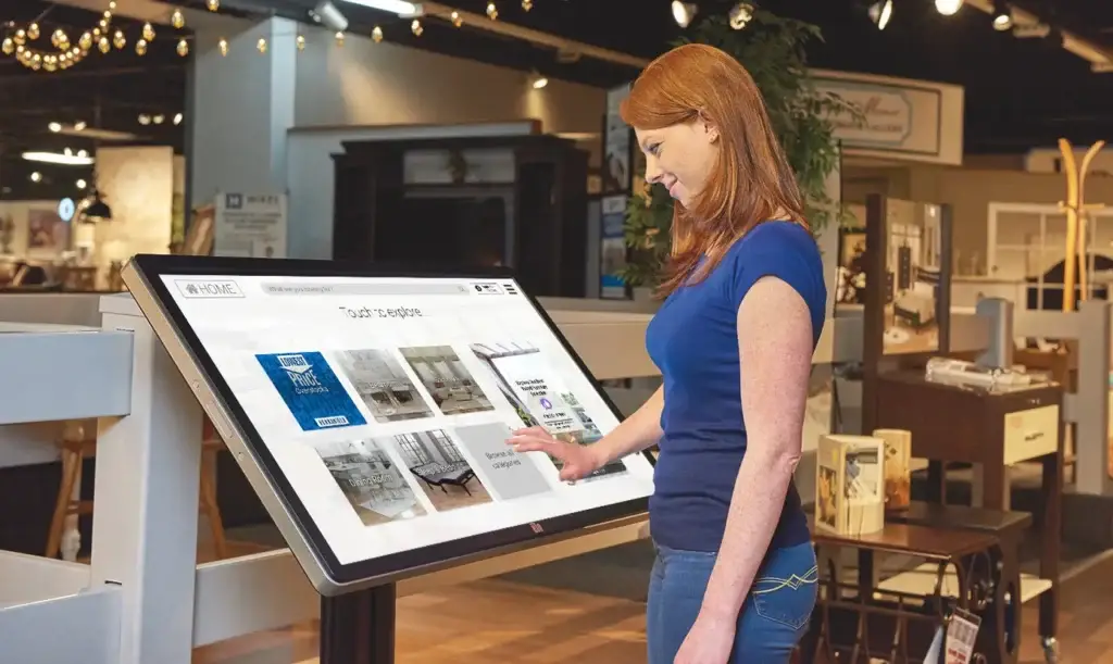 Image of female shopper browsing Overstocks on a Wonder kiosk in a furniture store