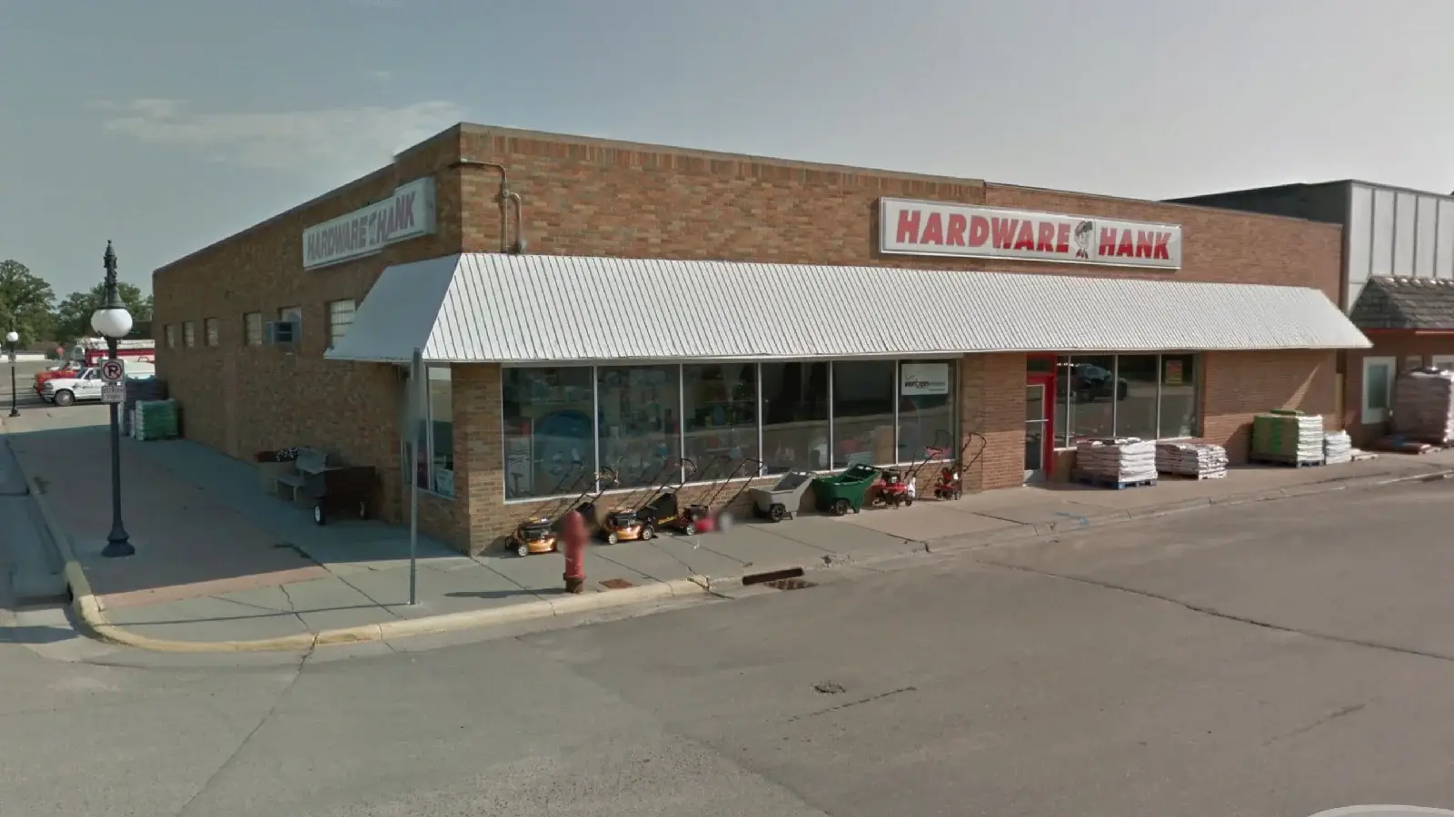 Hardware Hank storefront in Warren, Minnesota: a brick building with a white awning and lawn mowers out front Hardware Hank storefront in Warren, Minnesota: a brick building with a white awning and lawn mowers out front